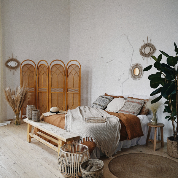 Chambre à coucher avec draps blancs et beiges. Décoration avec des plantes et des paniers en osier.